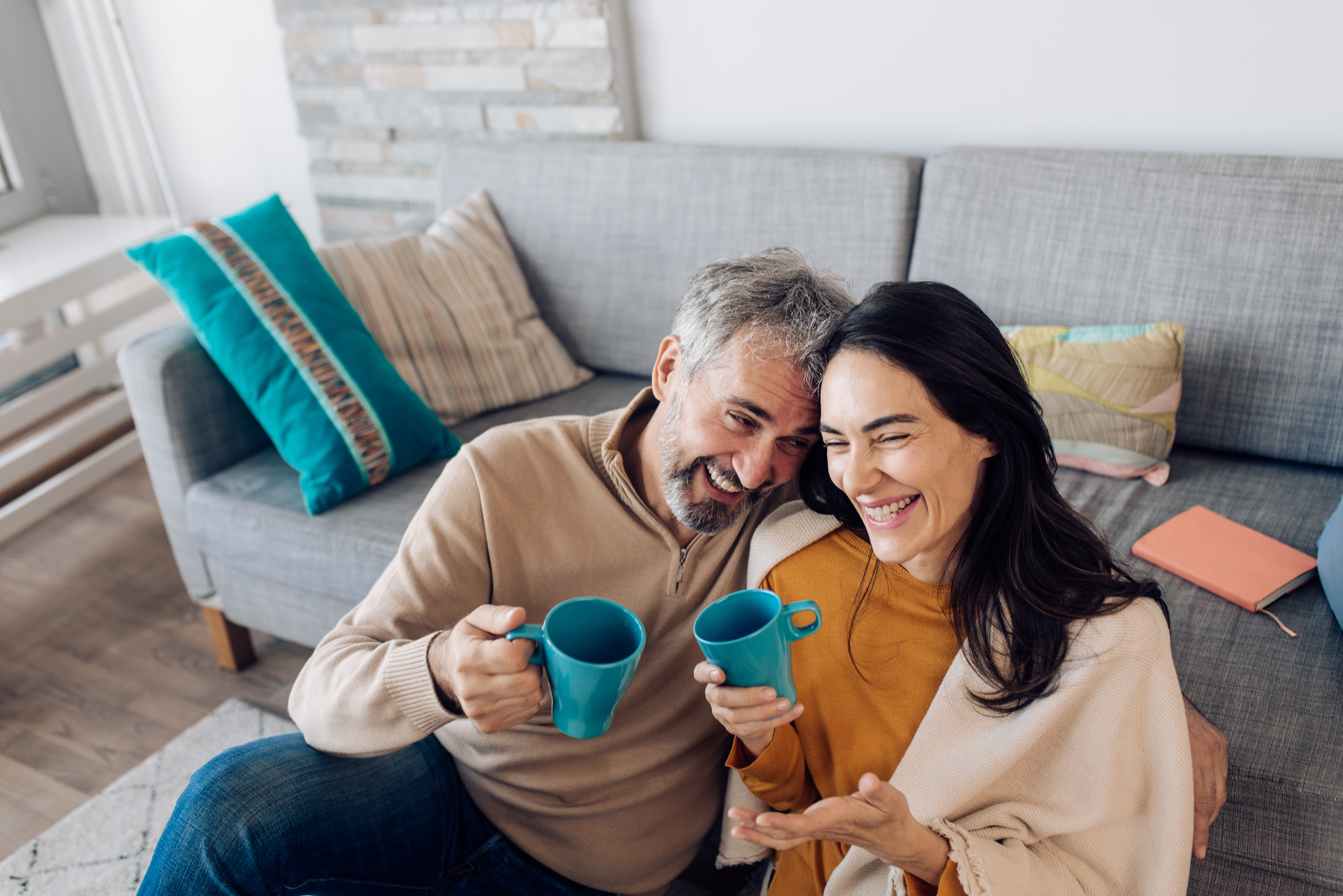 Couple in their home smiling and drinking coffee