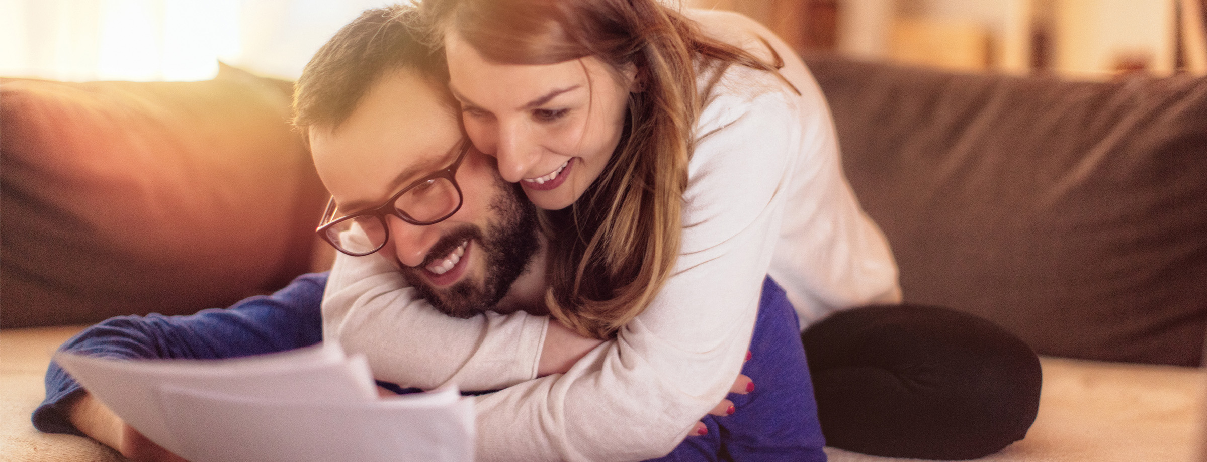 Couple smiling and hugging while look at a tax document.