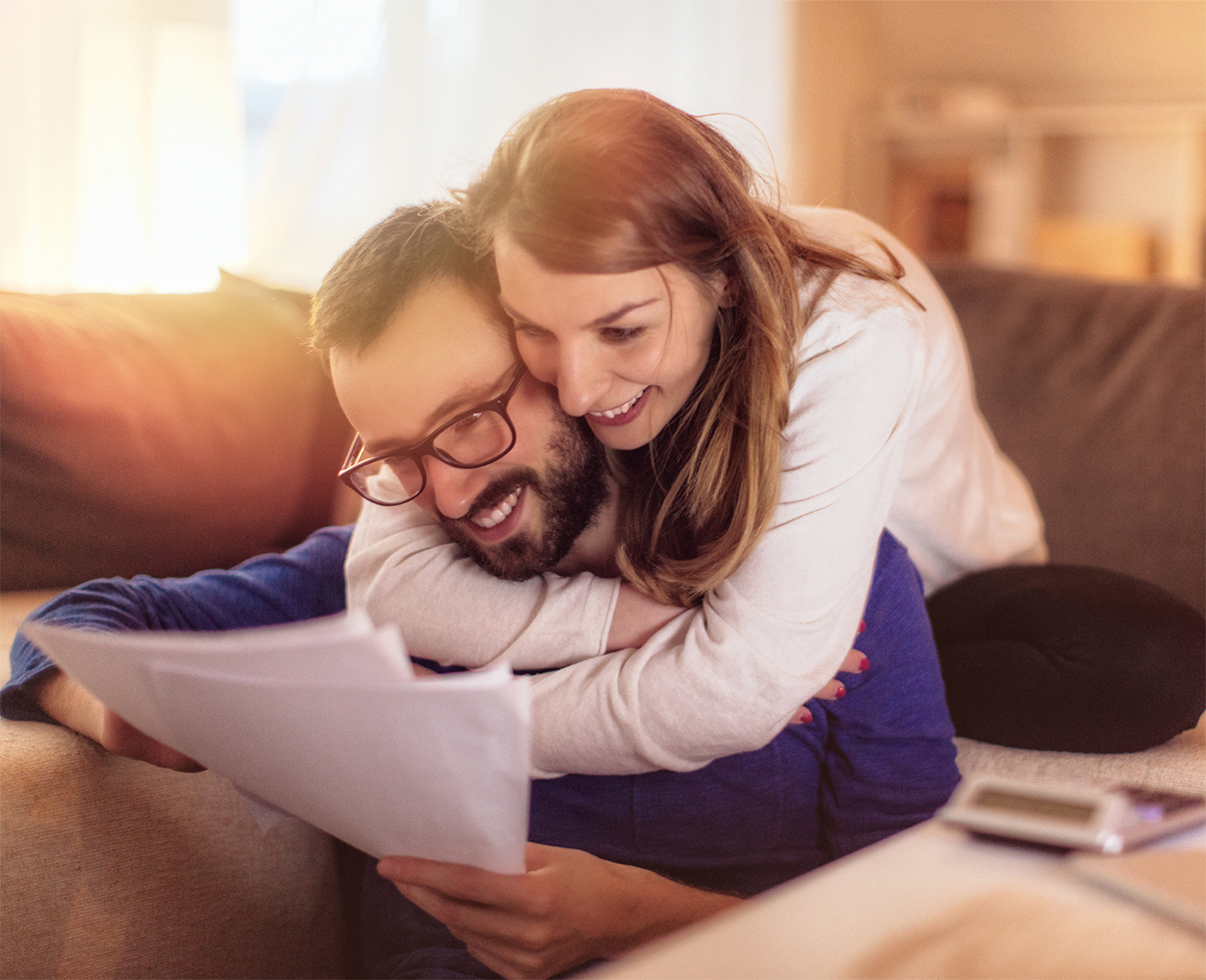 Couple smiling and hugging while look at a tax document.